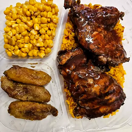 Jerk Chicken Plate — bone-in jerk thighs, yellow rice, corn and sweet plantains in a takeout box.